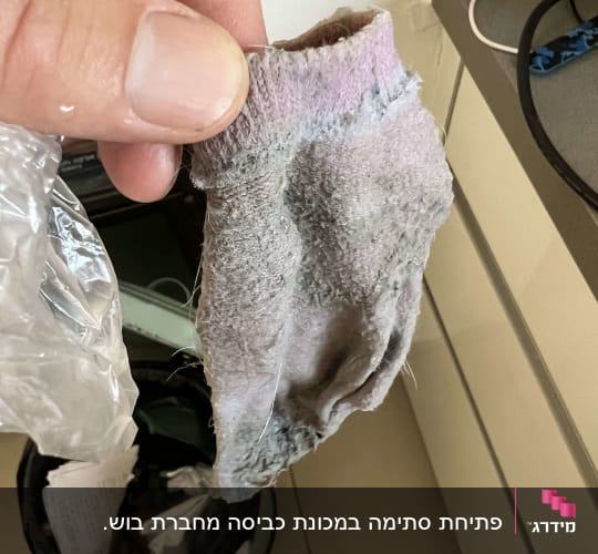 יד מחזיקה גרב ישן מעל פח אשפה